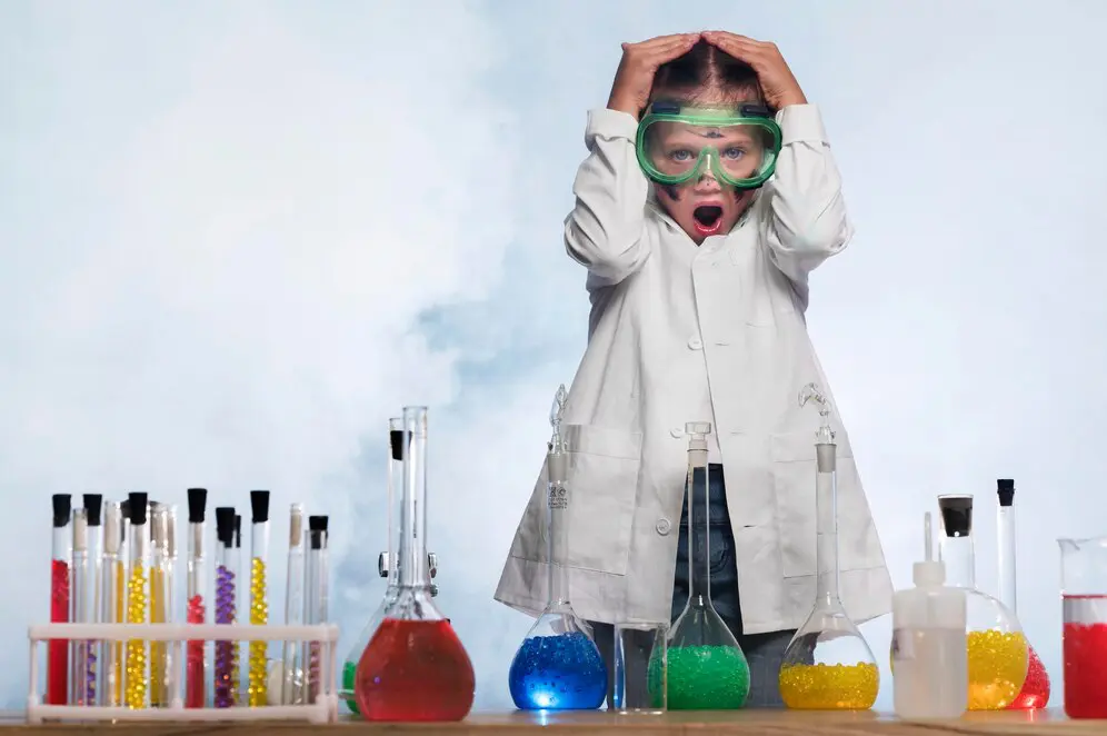 Child in lab coat reacts to experiments.