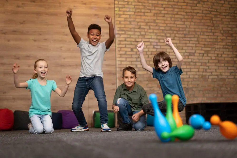 Children celebrating bowling game success indoors.