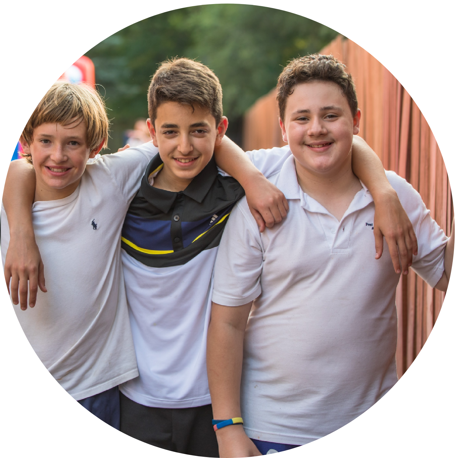 Three boys posing together, smiling happily.