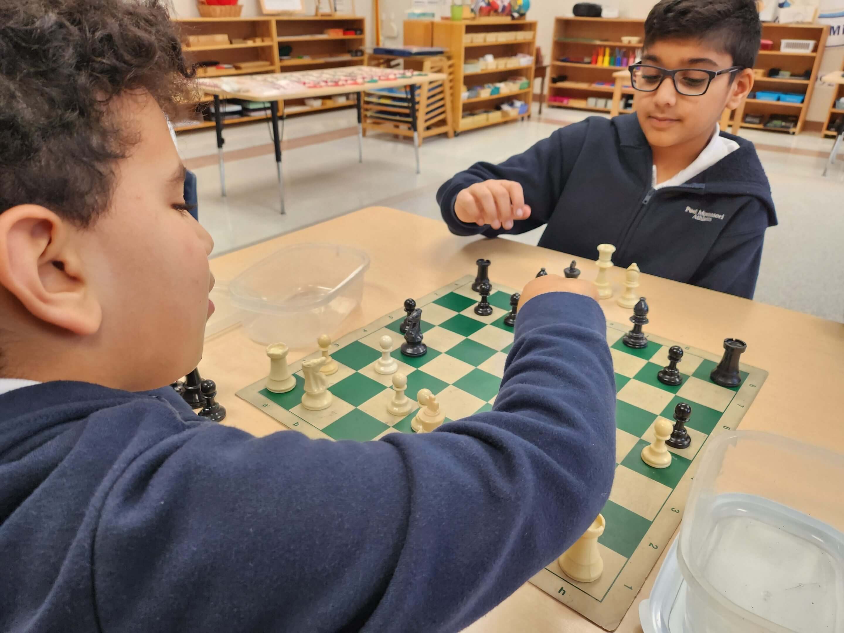 Two children playing chess at a table.