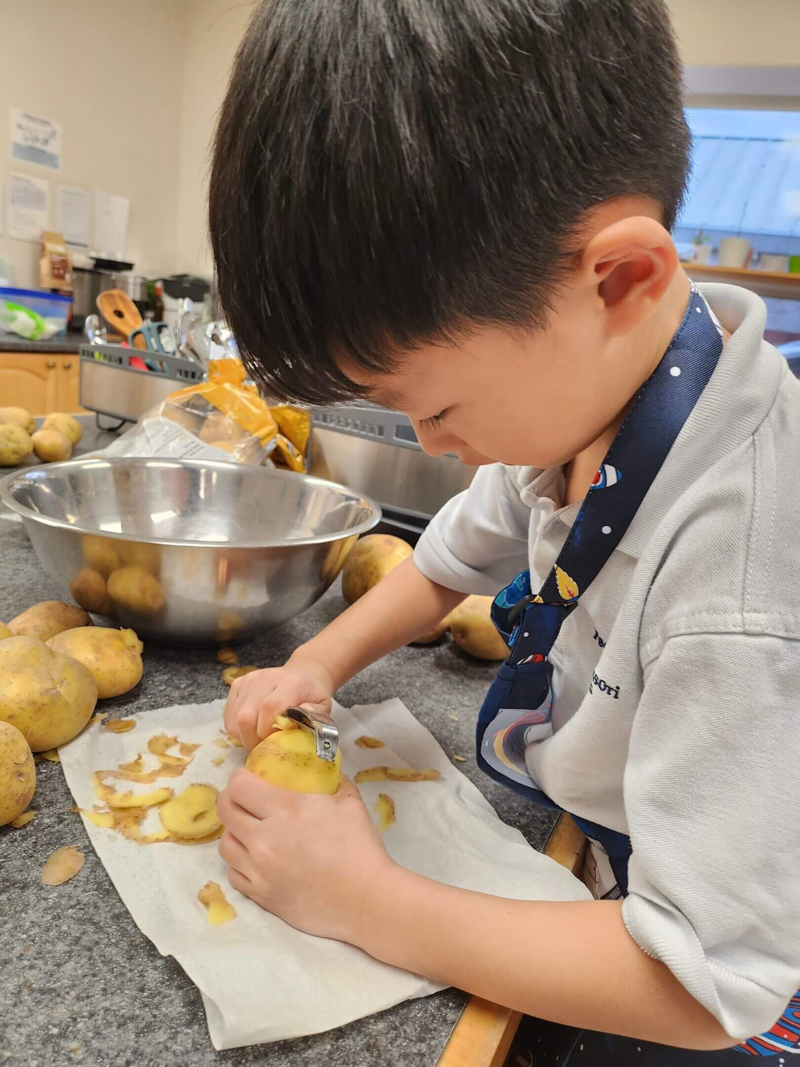 Child peeling potatoes in a kitchen.