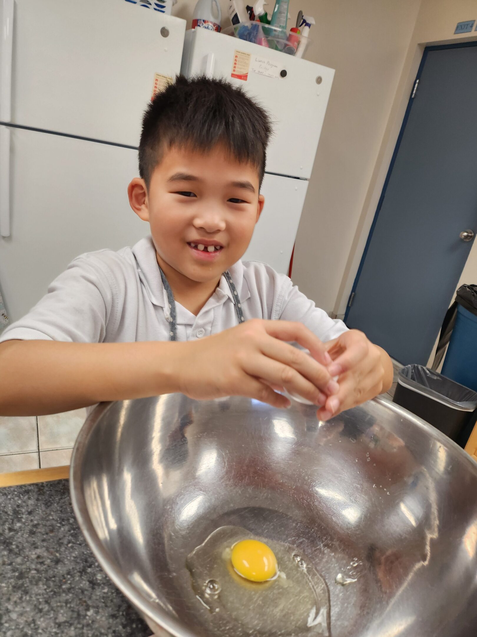 Child cracking an egg into a bowl.