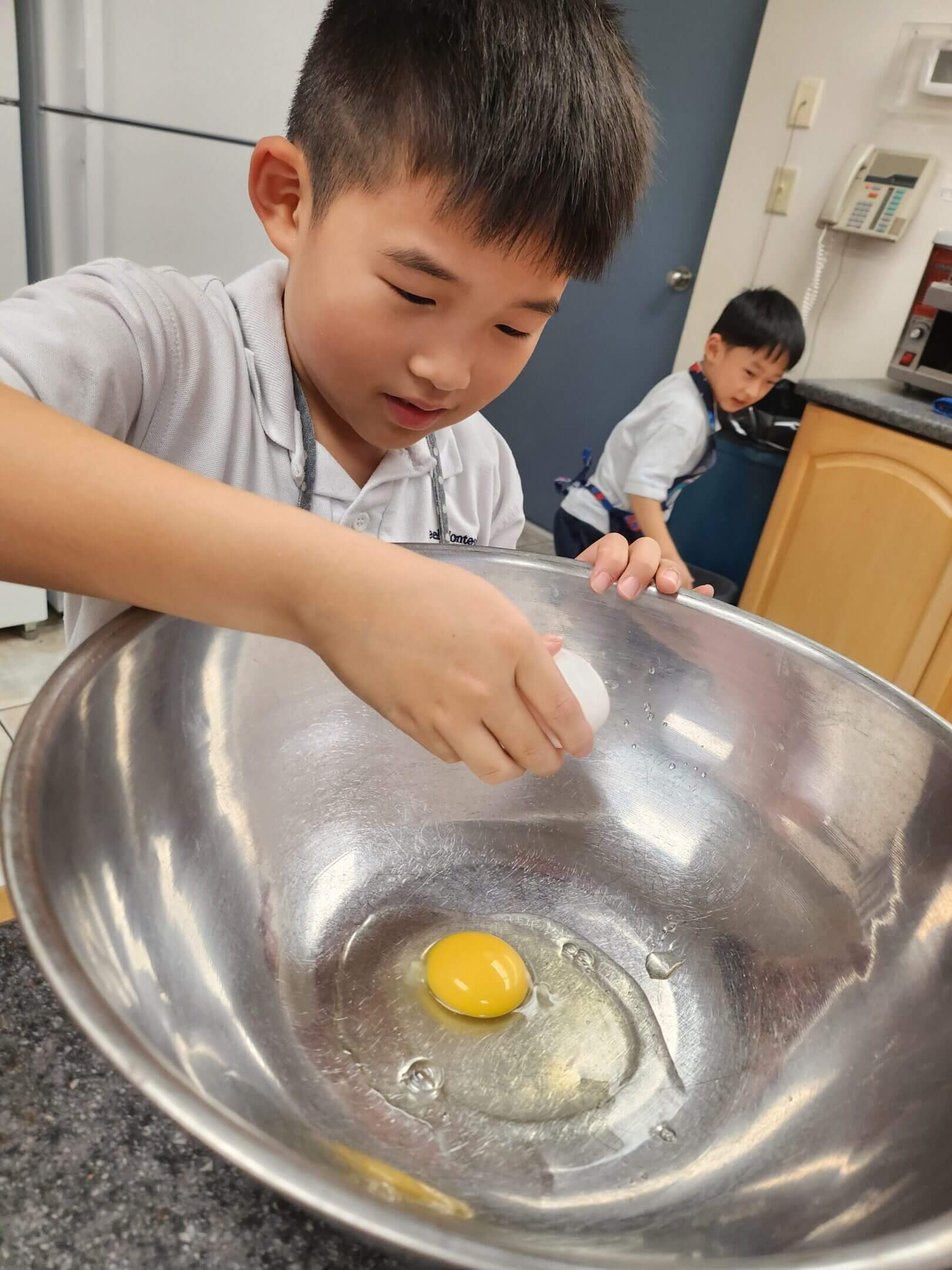 Child cracking an egg into a bowl.