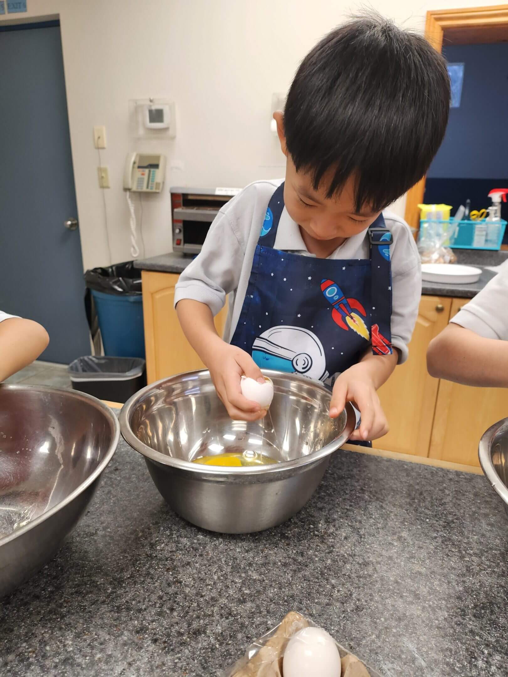 Child cracking an egg into a bowl.