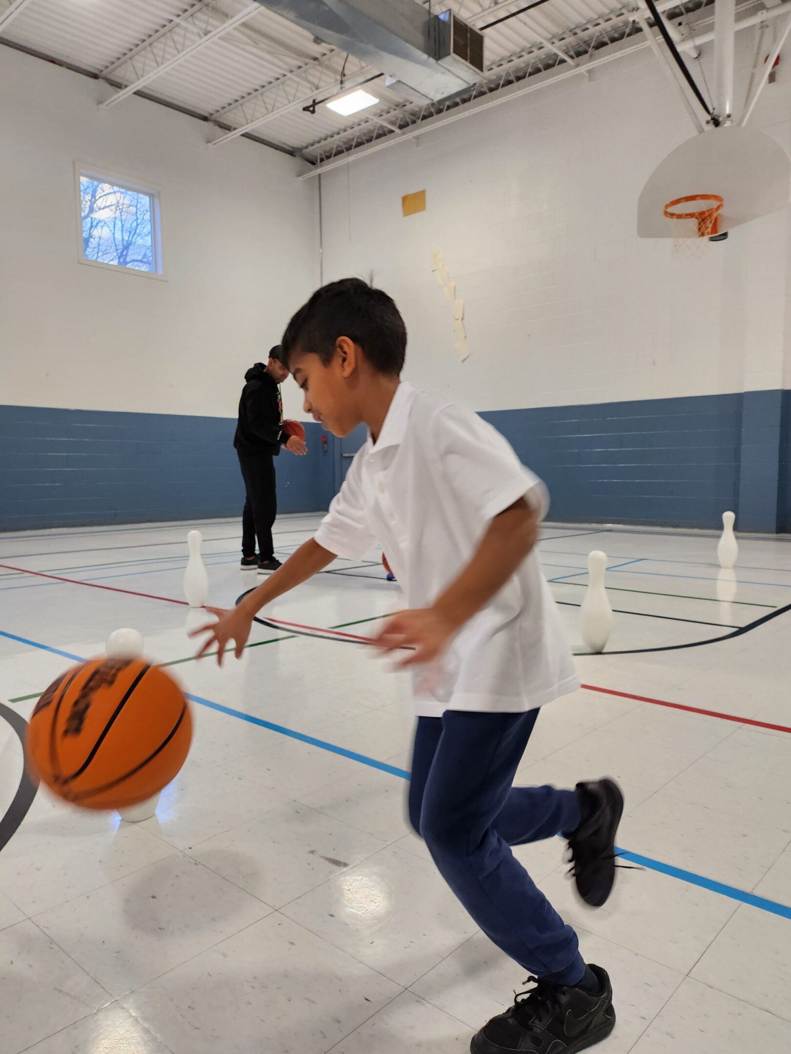 Child dribbling a basketball in gym.