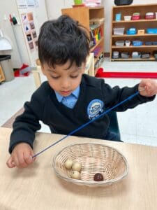 Child threading beads in a classroom activity.