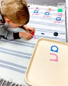 Child playing with colorful letter shapes.