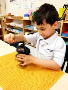 Child using a jar opener in class.