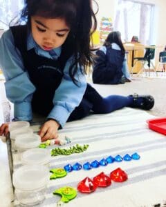 Child organizing colorful learning materials on rug.