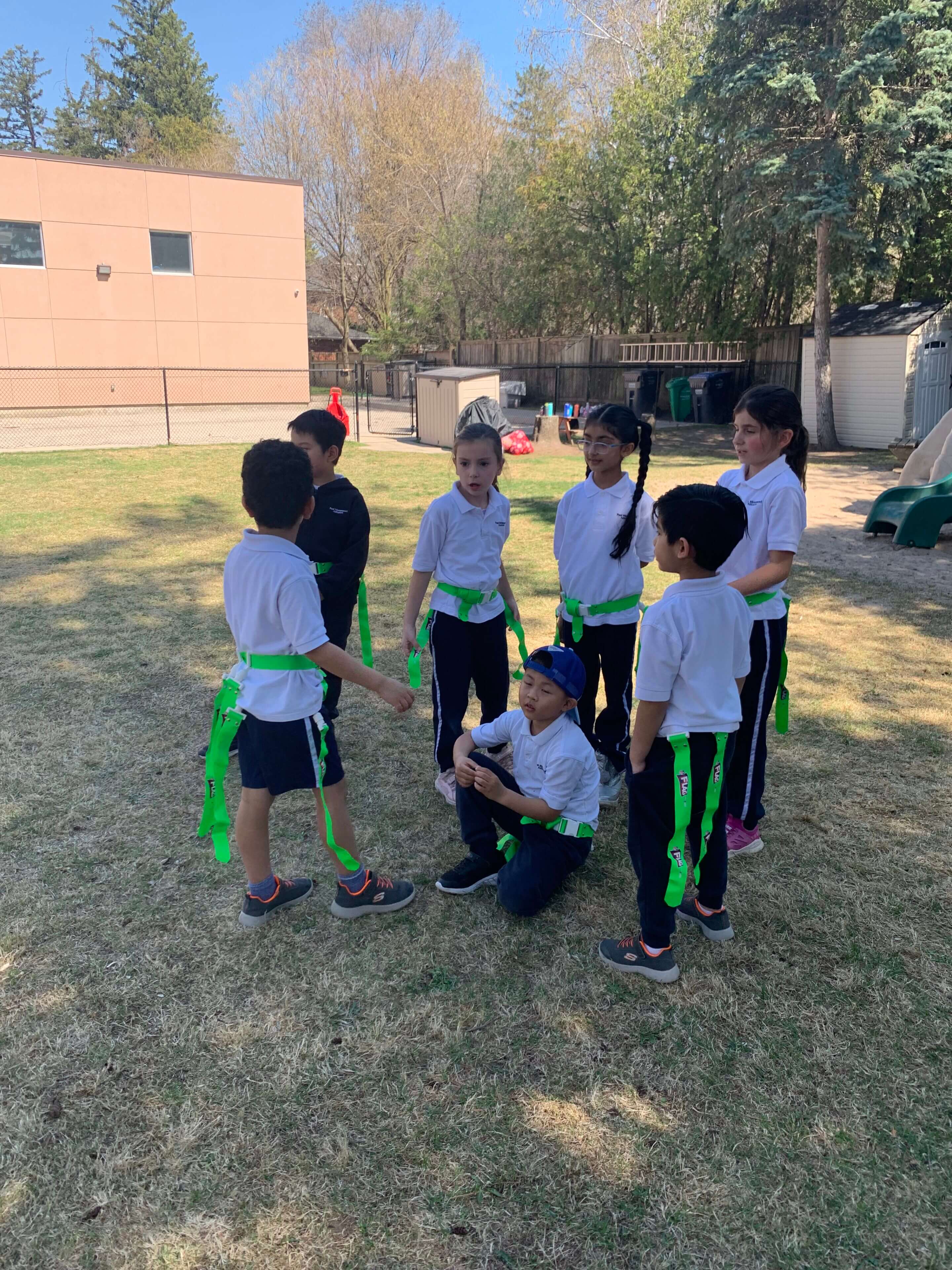 Children playing outdoors in athletic uniforms.