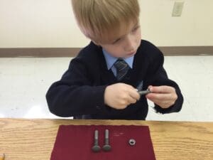 Child assembling metal bolts and nuts.