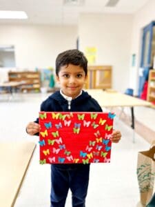 Boy holding butterfly art piece proudly.