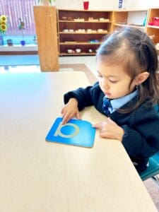 Child learning with a blue educational card.