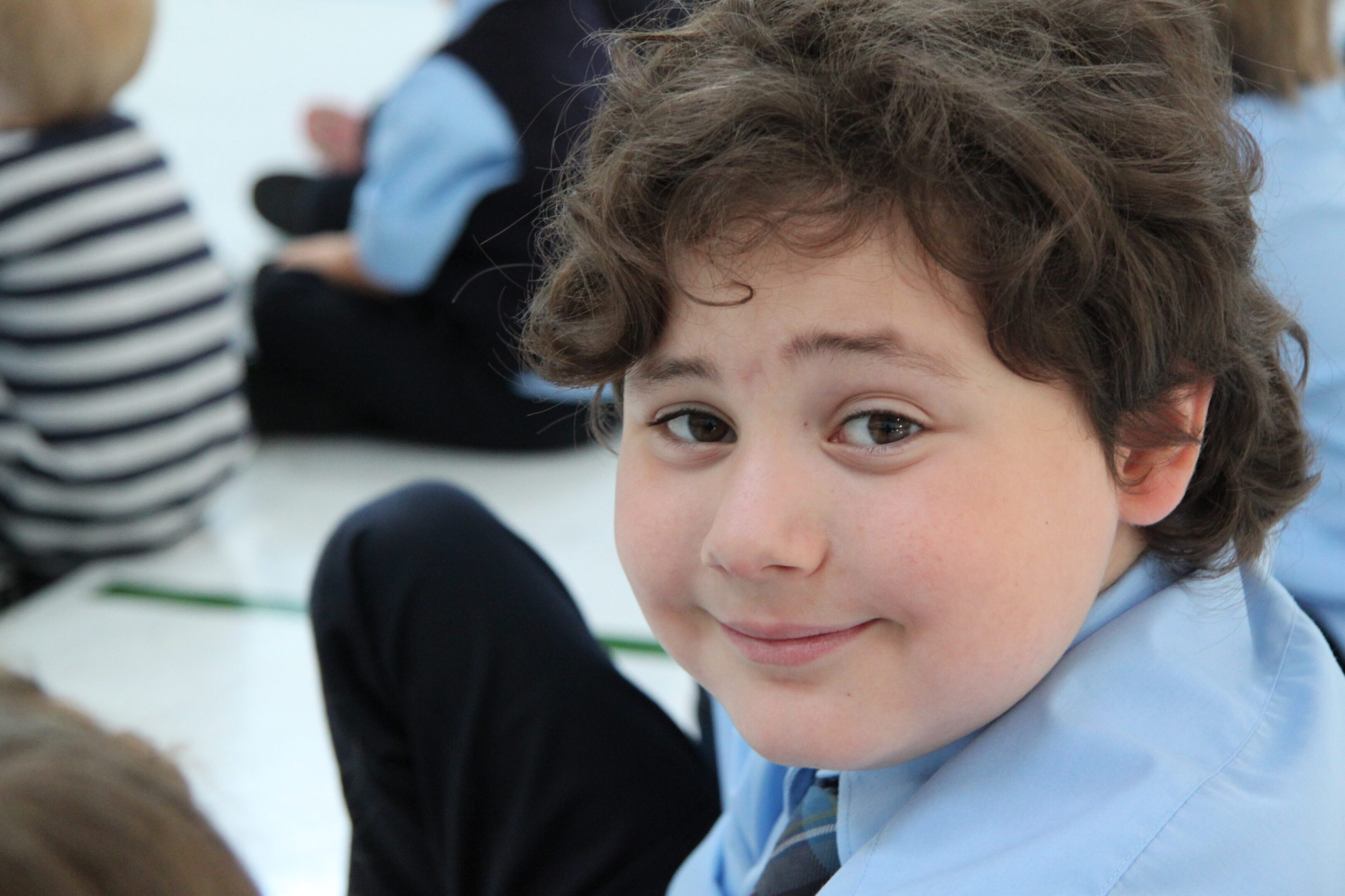 Smiling boy in a classroom setting.