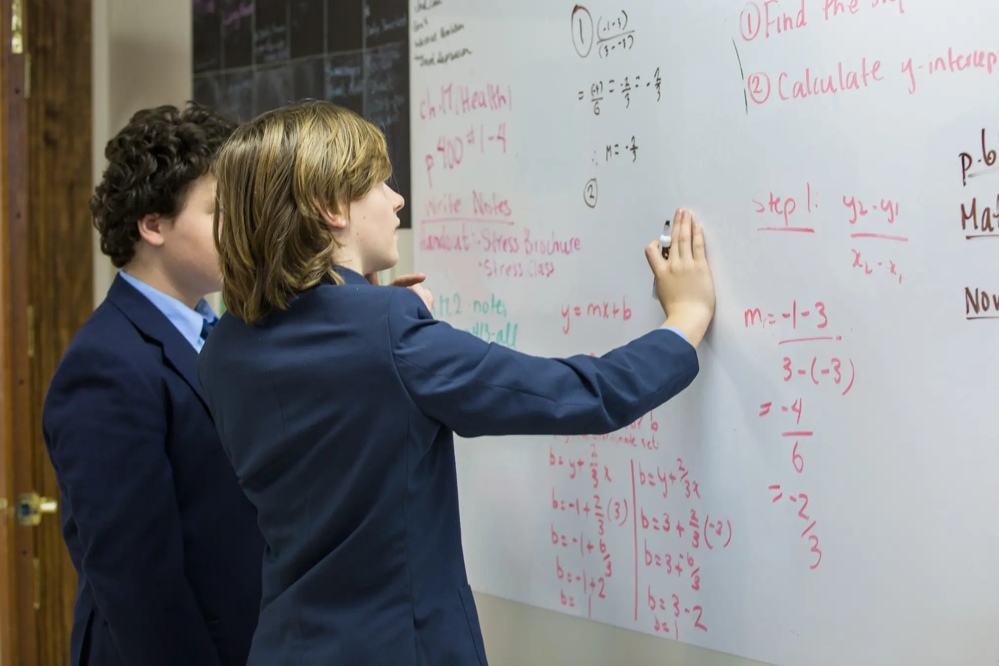 Students writing on a whiteboard together.