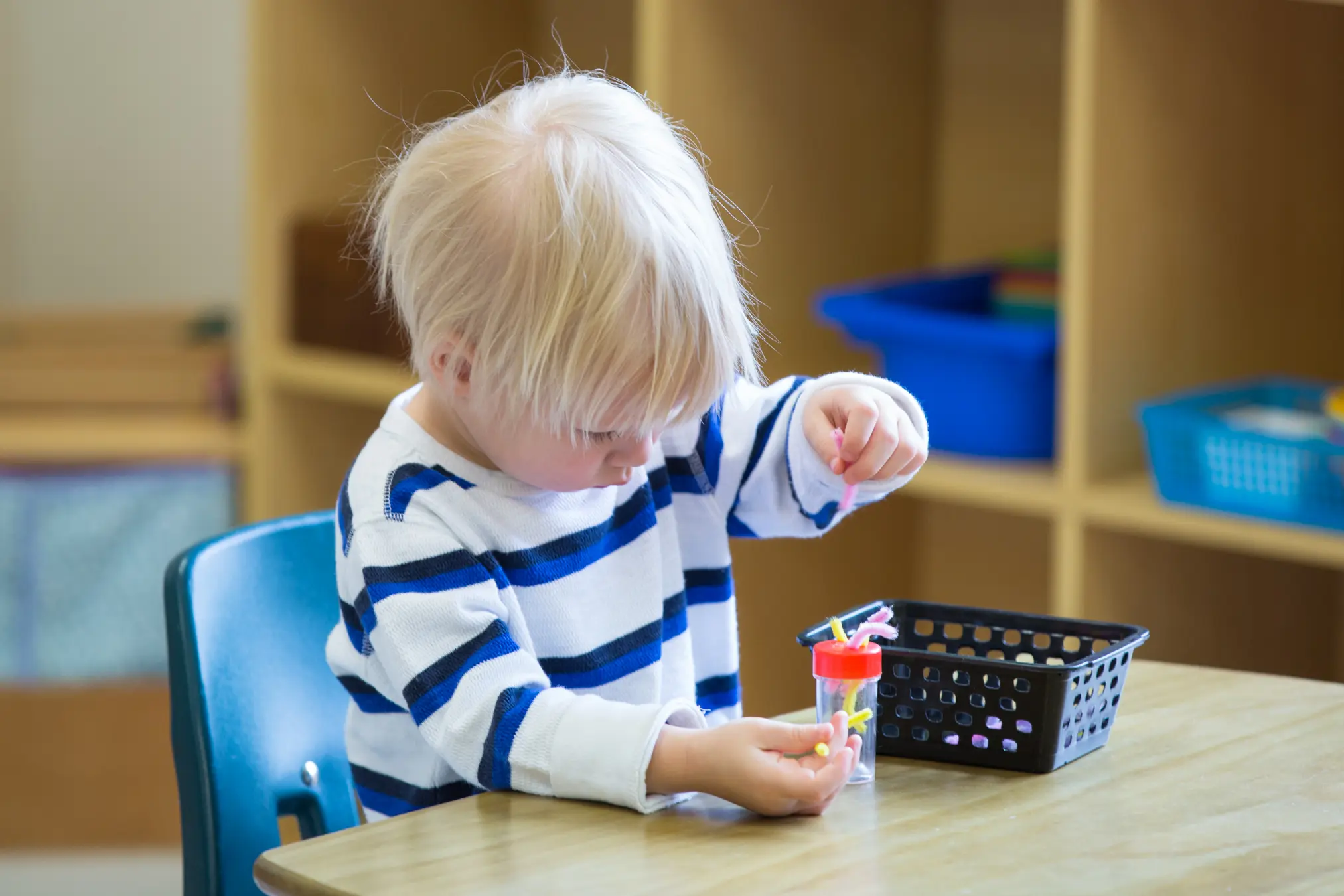 Child playing with colorful sorting tools.