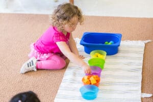 Child sorting colorful shapes on a mat.