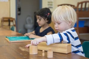 Children playing with wooden blocks indoors.