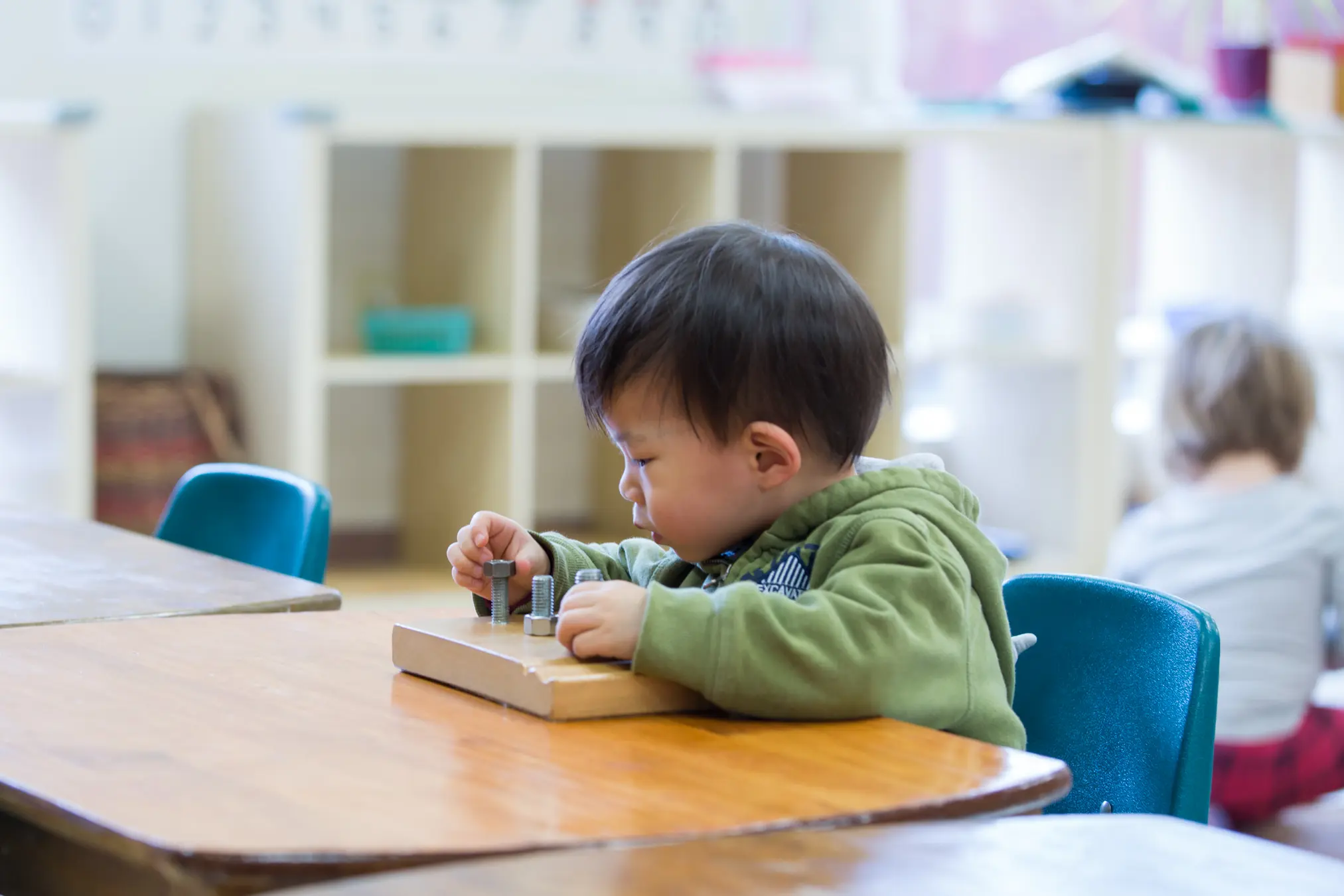 Child engaging with educational activity at table.