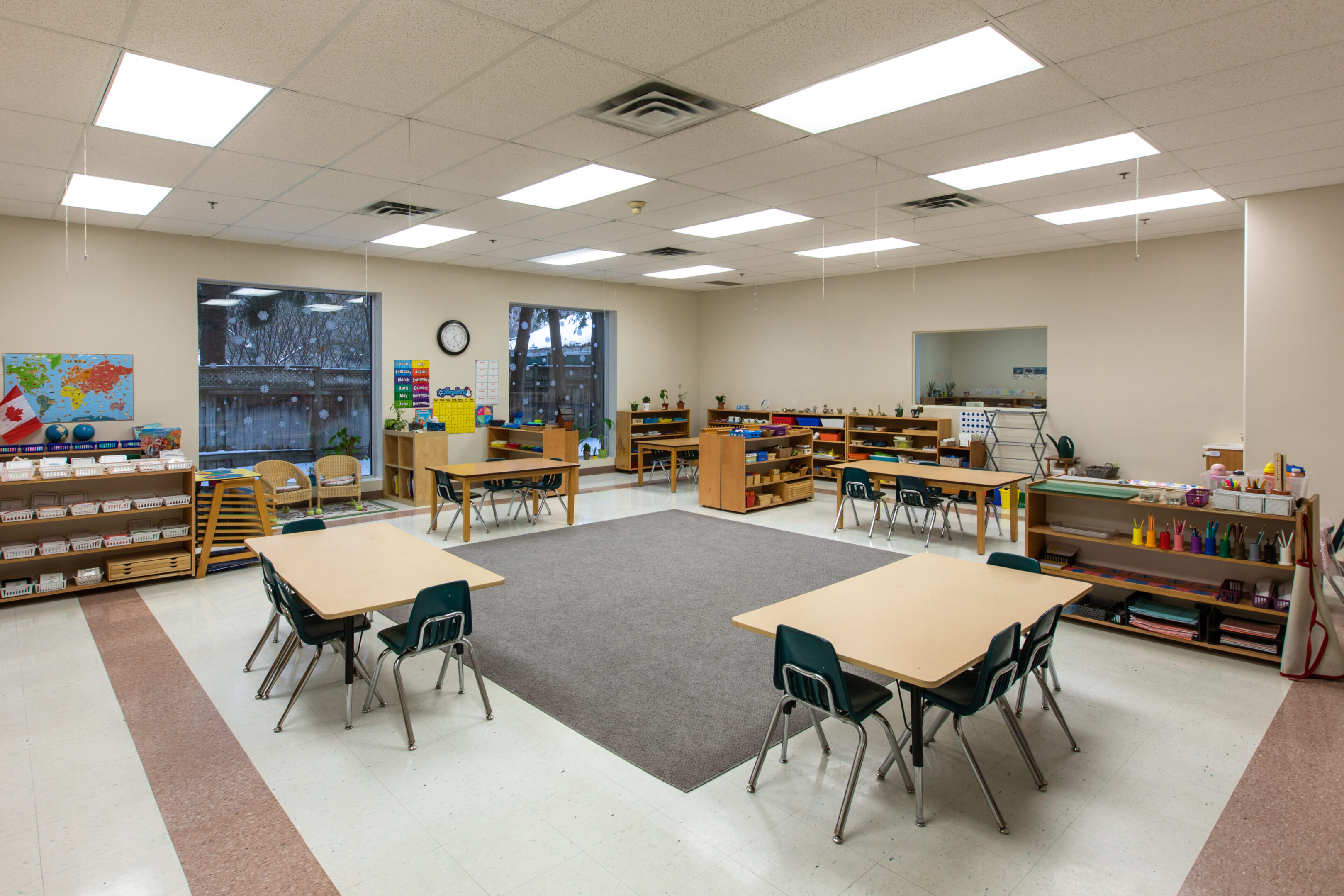 Classroom with tables and storage shelves.