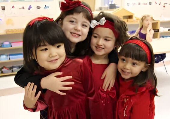 Four girls in red dresses smiling together.